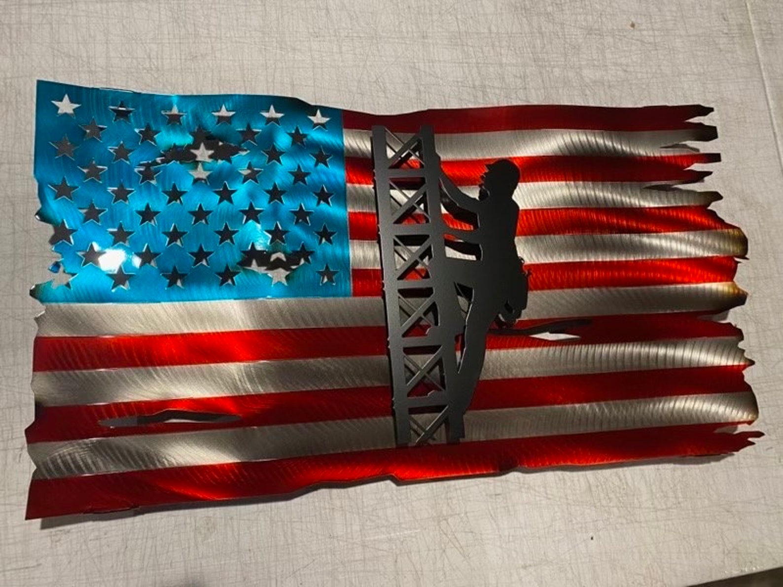 Metal American flag with lineman climbing cell tower silhouette