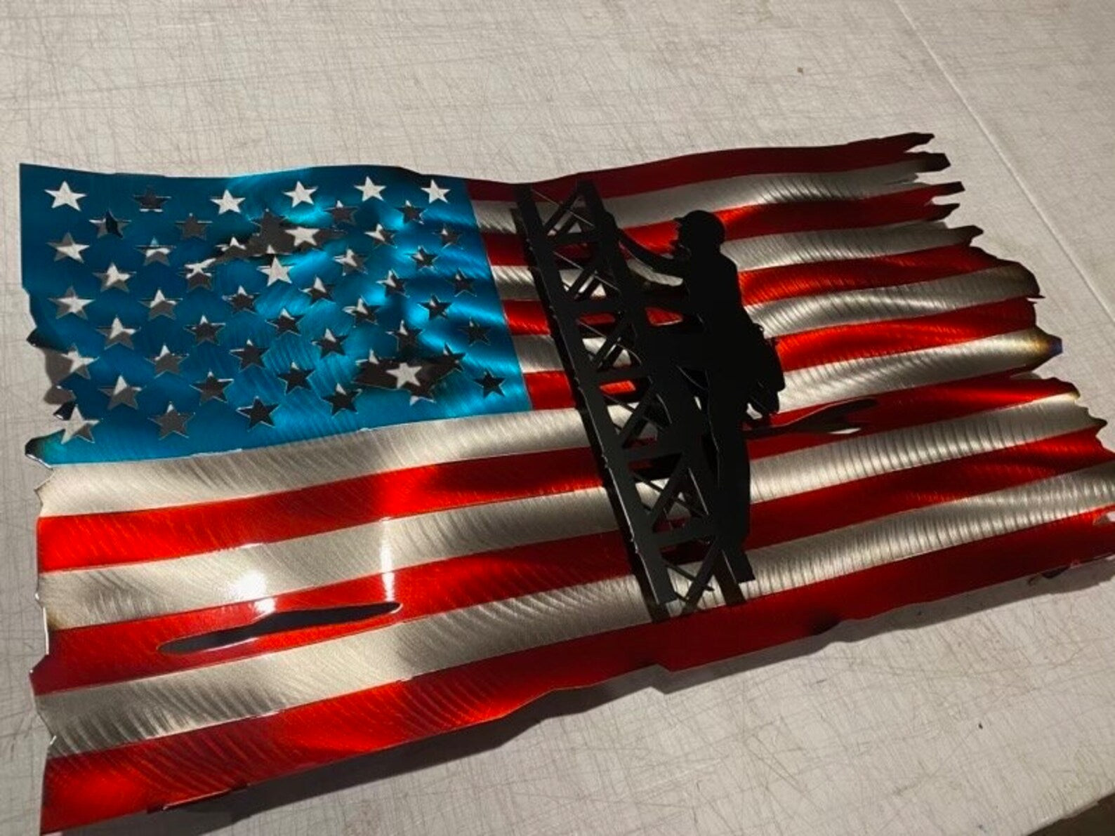 Metal American flag with lineman climbing cell tower silhouette