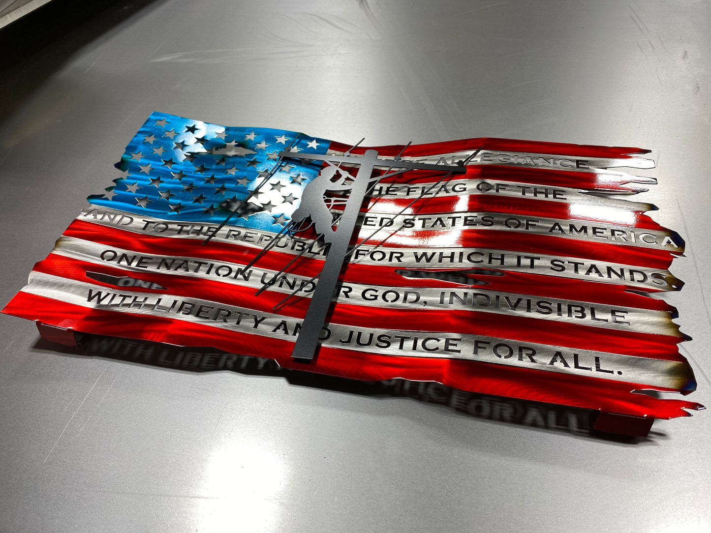 Distressed metal lineman flag with Pledge of Allegiance, crafted from American steel with wave pattern and powder coat finish