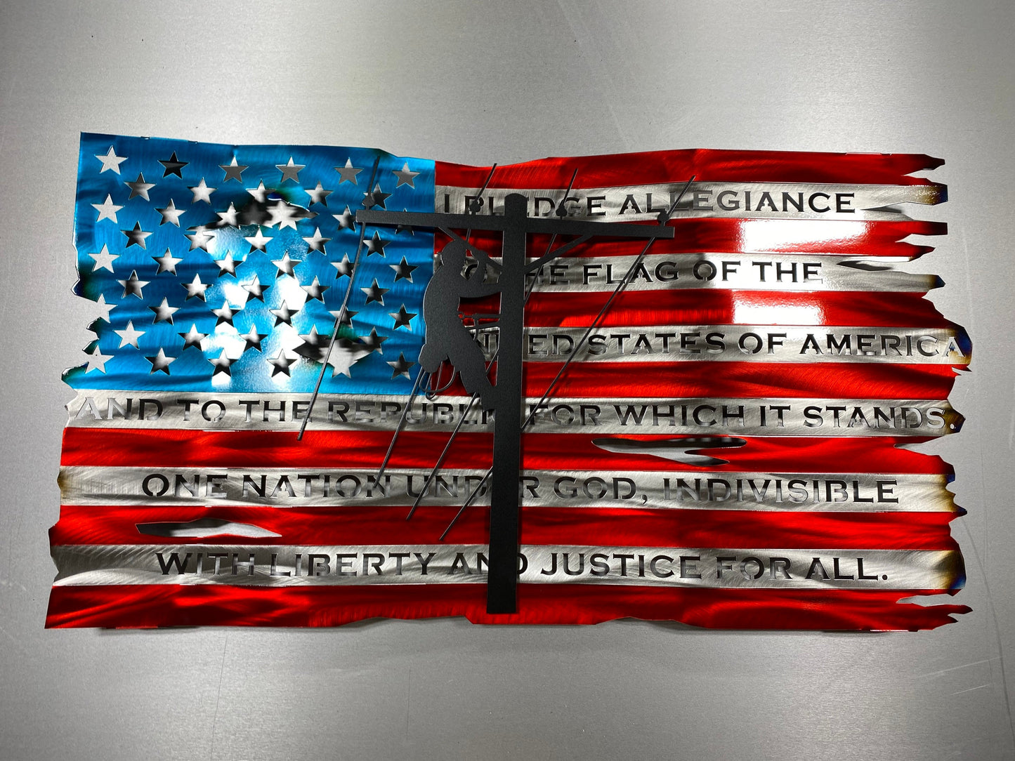 Distressed metal lineman flag with Pledge of Allegiance, crafted from American steel with wave pattern and powder coat finish