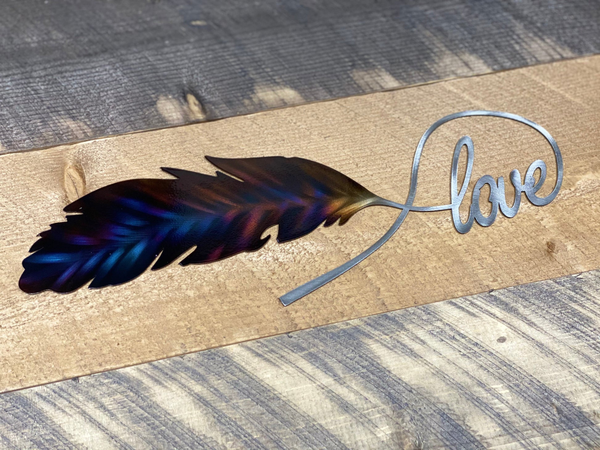 Love Feather metal wall art, handcrafted from American steel, heat-treated for blue and purple hues, and finished with a clear powder coat by CnS CnC.