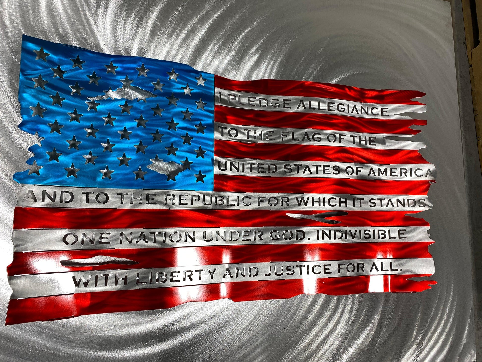 Pledge of Allegiance metal flag with hand-formed waves, heat patina finish, and floating wall mount design, measuring 24 inches wide.