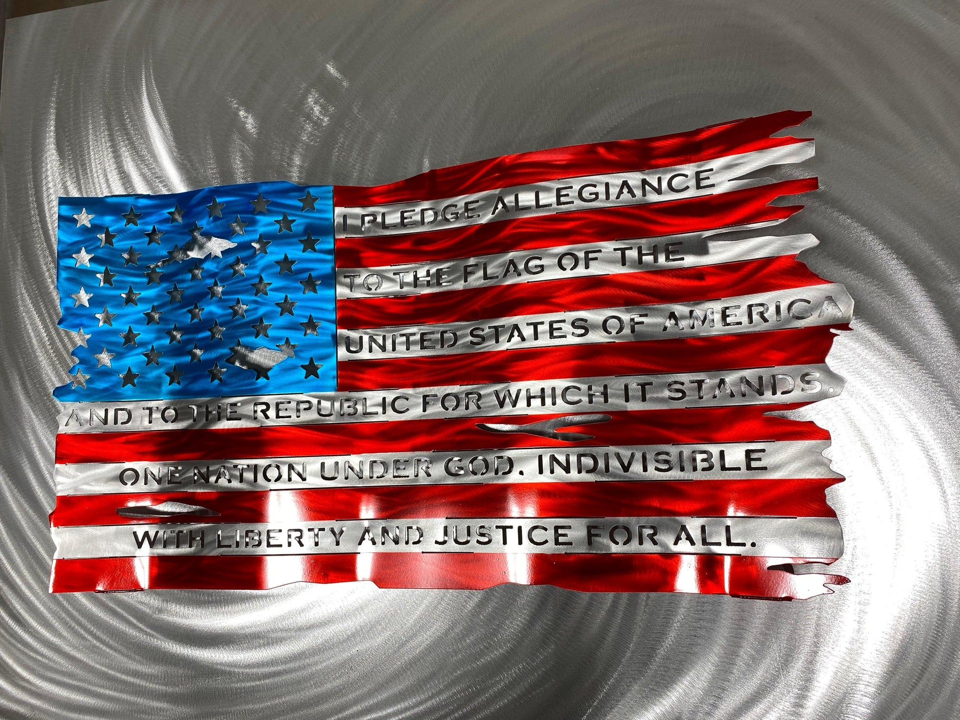 Pledge of Allegiance metal flag with hand-formed waves, heat patina finish, and floating wall mount design, measuring 24 inches wide.