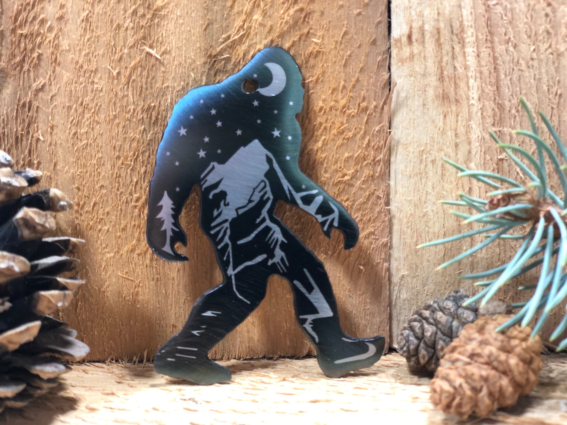 Sasquatch Keychain, handcrafted metal keychain featuring laser-engraved Bigfoot design, nighttime landscape, and clear powder coat finish by CnS CnC.