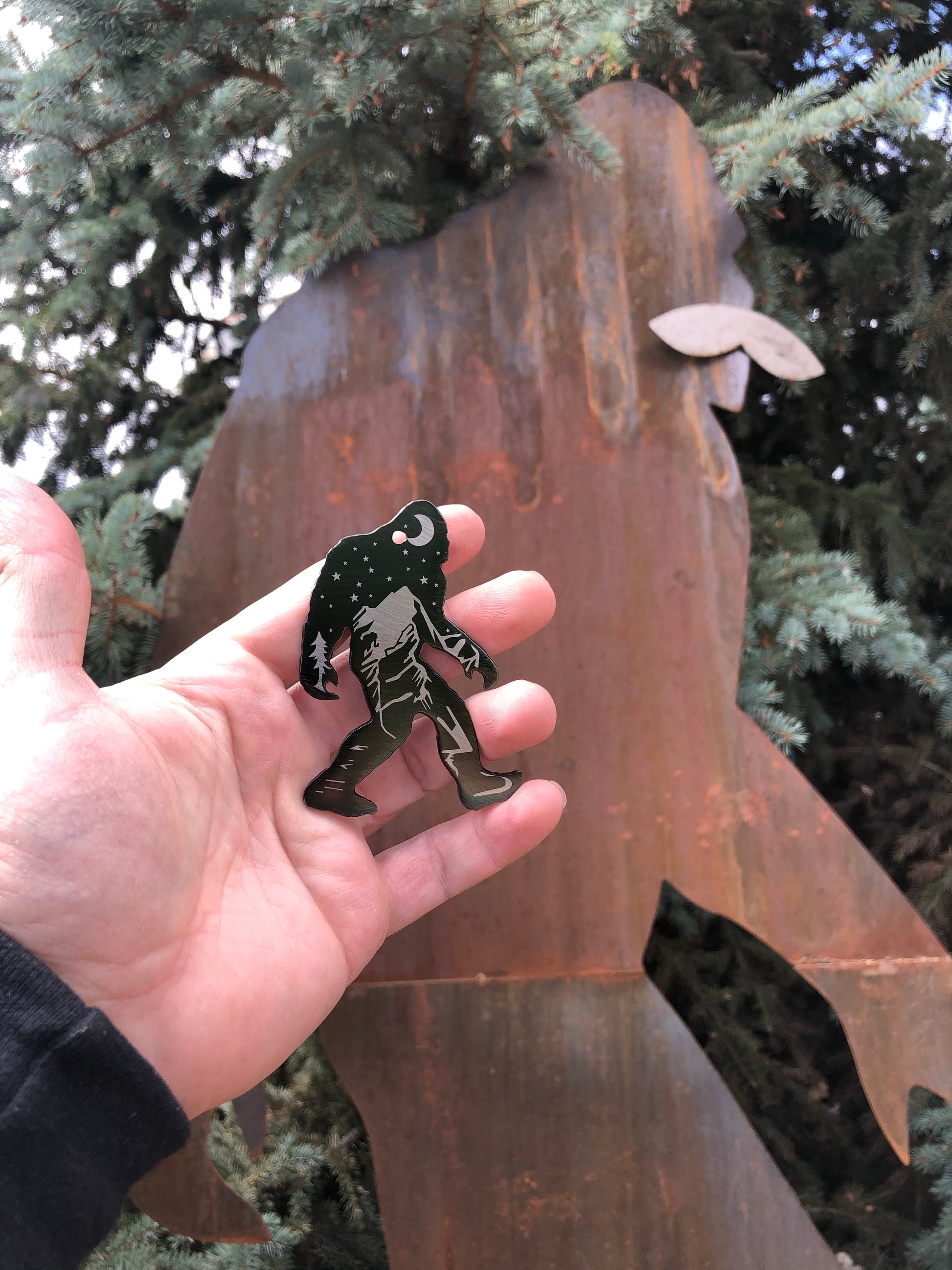 Sasquatch Keychain, handcrafted metal keychain featuring laser-engraved Bigfoot design, nighttime landscape, and clear powder coat finish by CnS CnC.