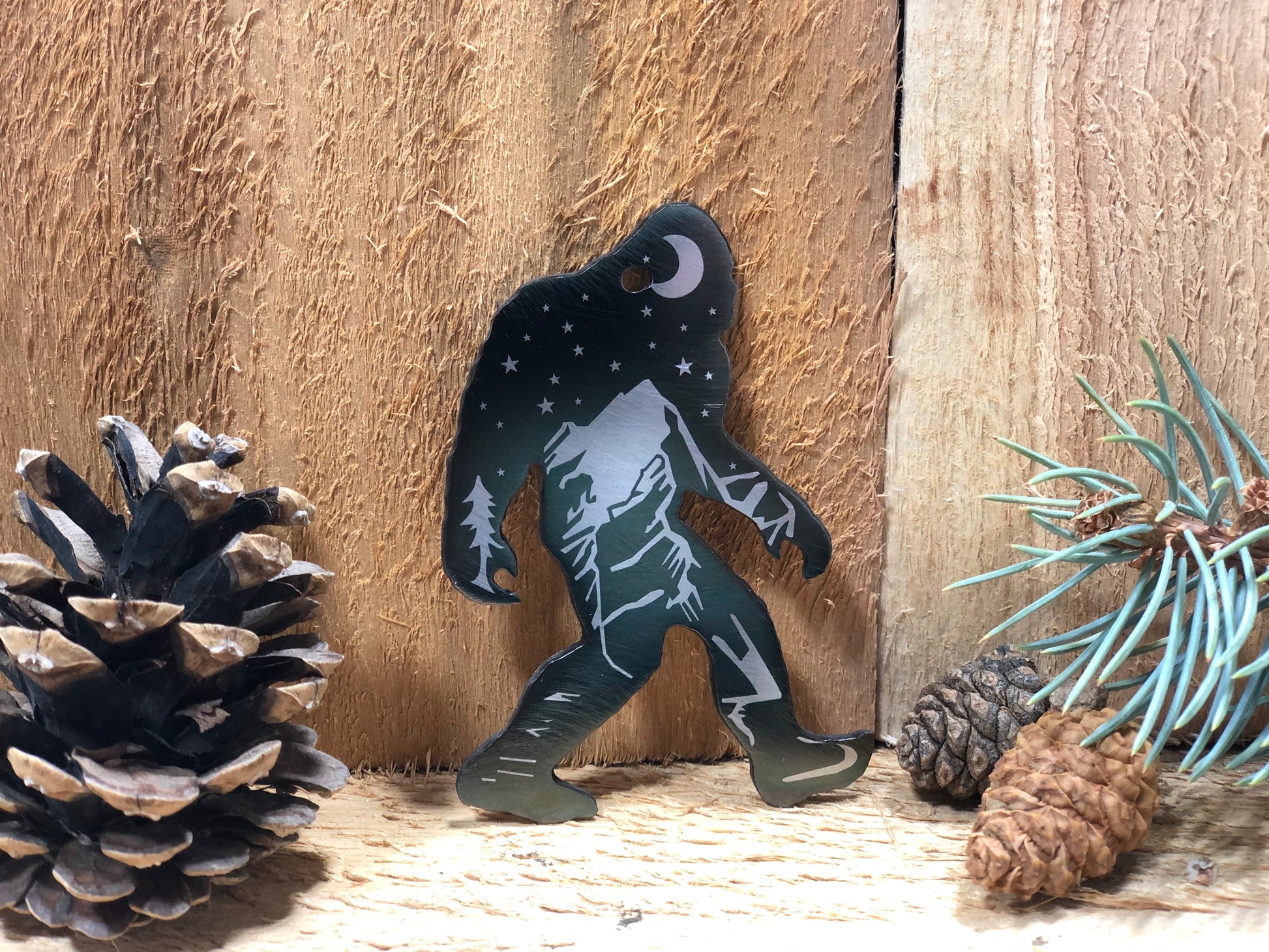 Sasquatch Keychain, handcrafted metal keychain featuring laser-engraved Bigfoot design, nighttime landscape, and clear powder coat finish by CnS CnC.