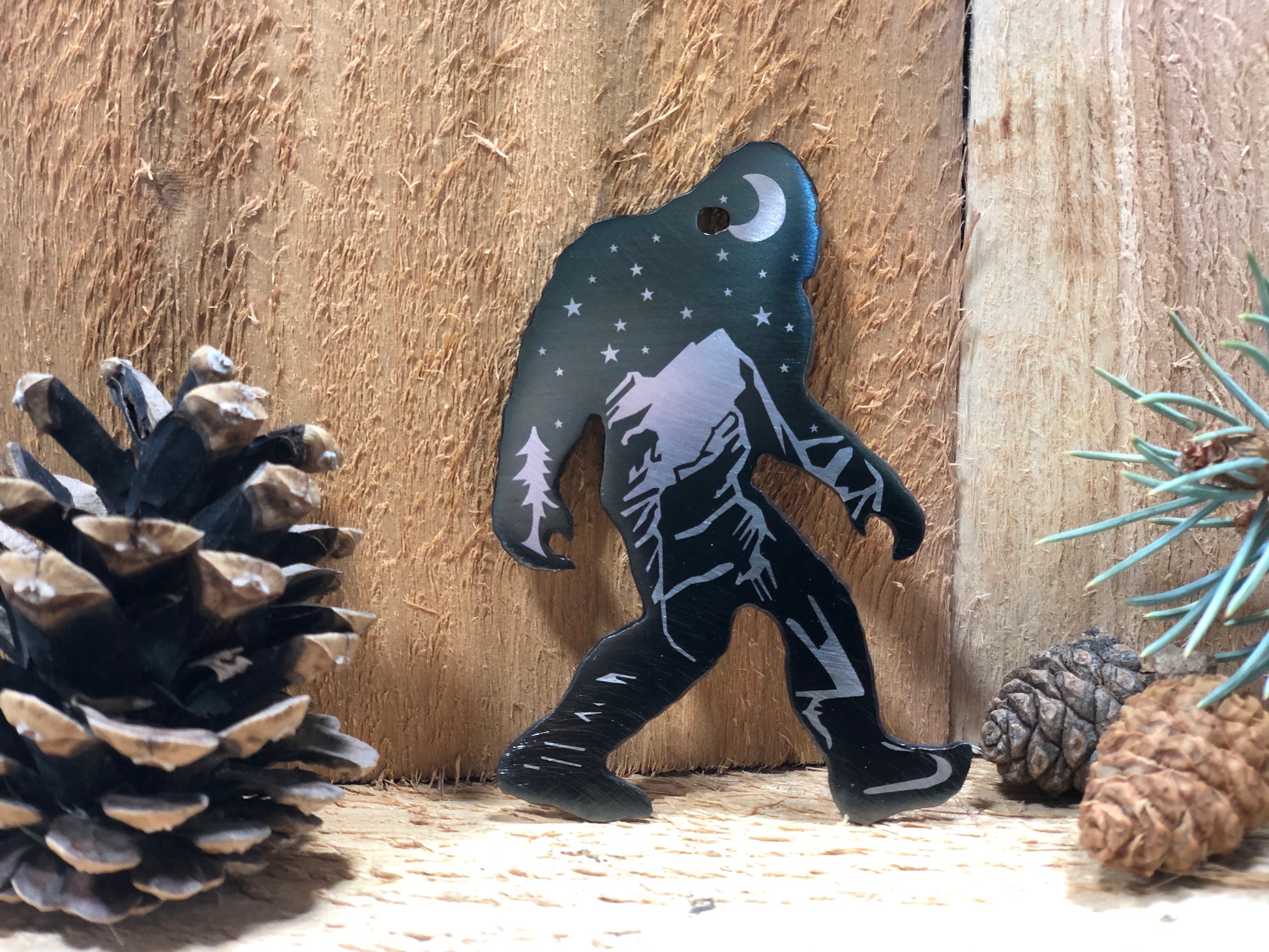 Sasquatch Keychain, handcrafted metal keychain featuring laser-engraved Bigfoot design, nighttime landscape, and clear powder coat finish by CnS CnC.