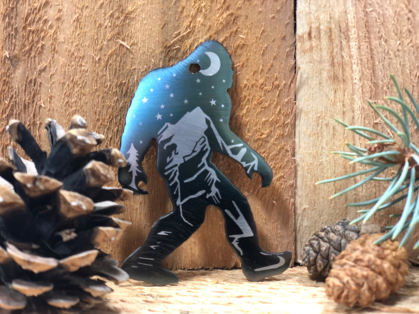 Sasquatch Keychain, handcrafted metal keychain featuring laser-engraved Bigfoot design, nighttime landscape, and clear powder coat finish by CnS CnC.