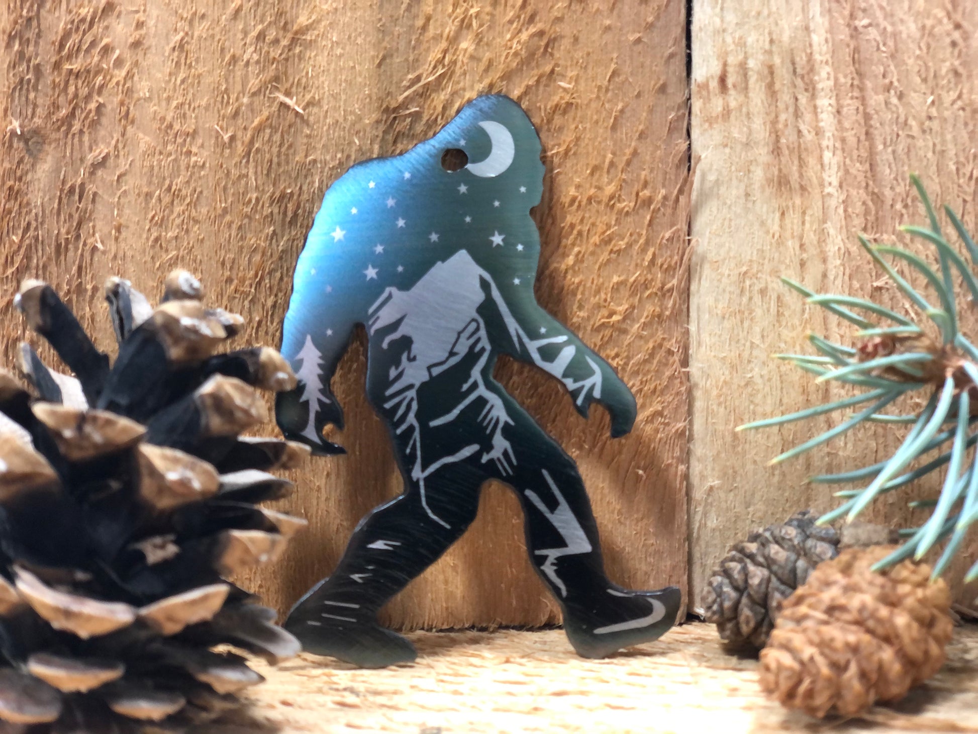 Sasquatch Keychain, handcrafted metal keychain featuring laser-engraved Bigfoot design, nighttime landscape, and clear powder coat finish by CnS CnC.