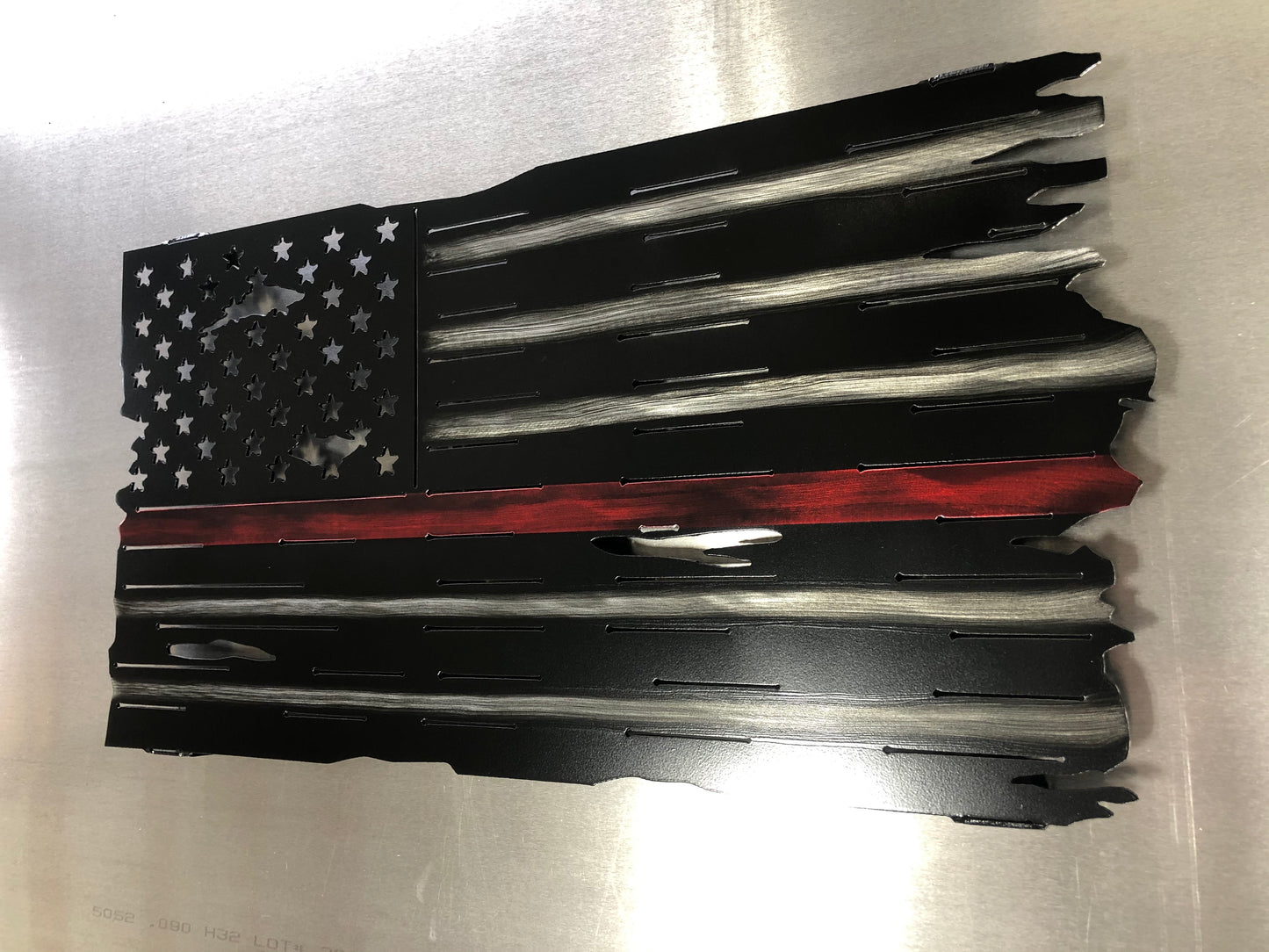 Thin Red Line Distressed American Flag made from metal, featuring a rugged design honoring firefighters. Perfect for home or station display.