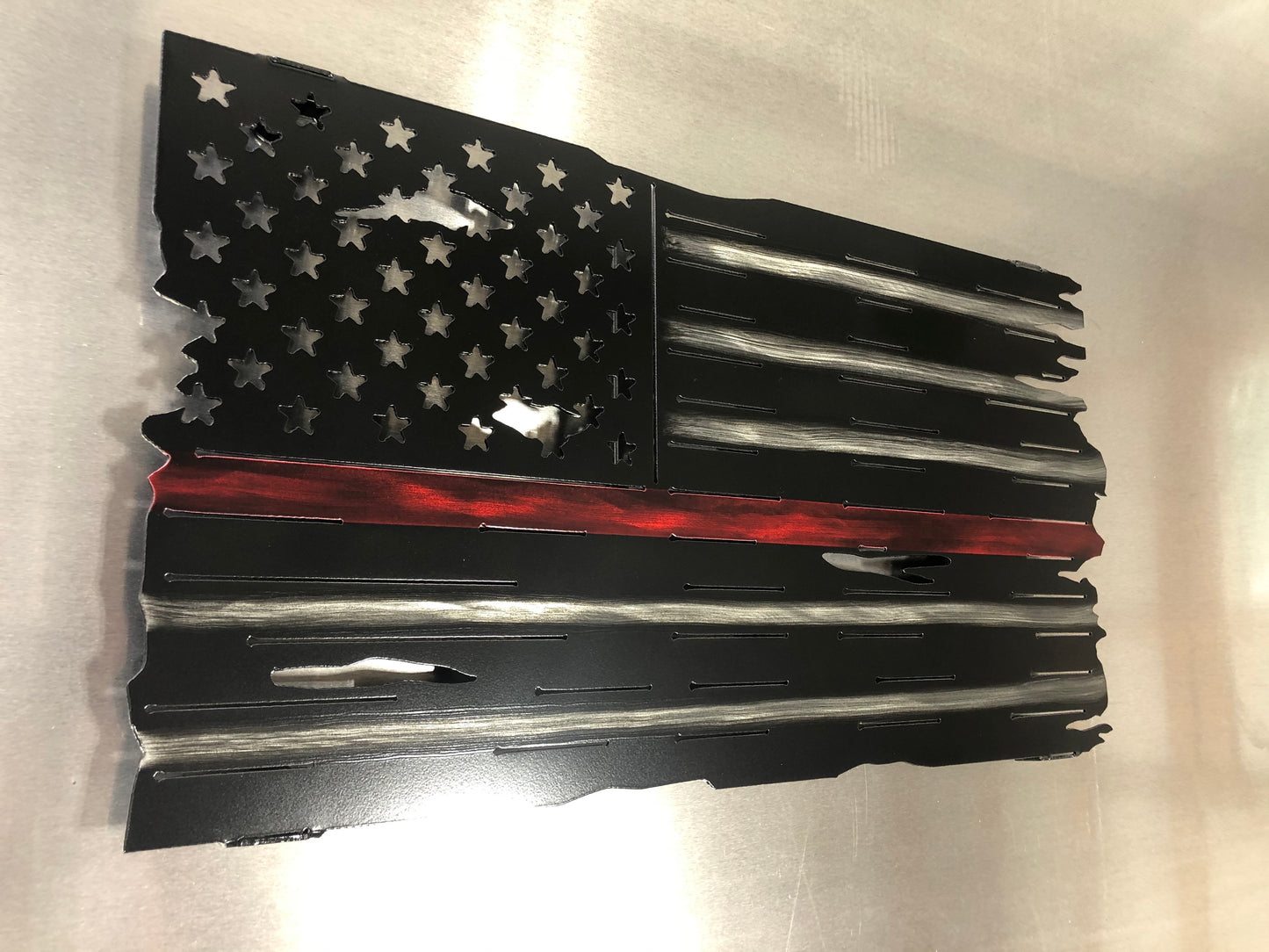 Thin Red Line Distressed American Flag made from metal, featuring a rugged design honoring firefighters. Perfect for home or station display.