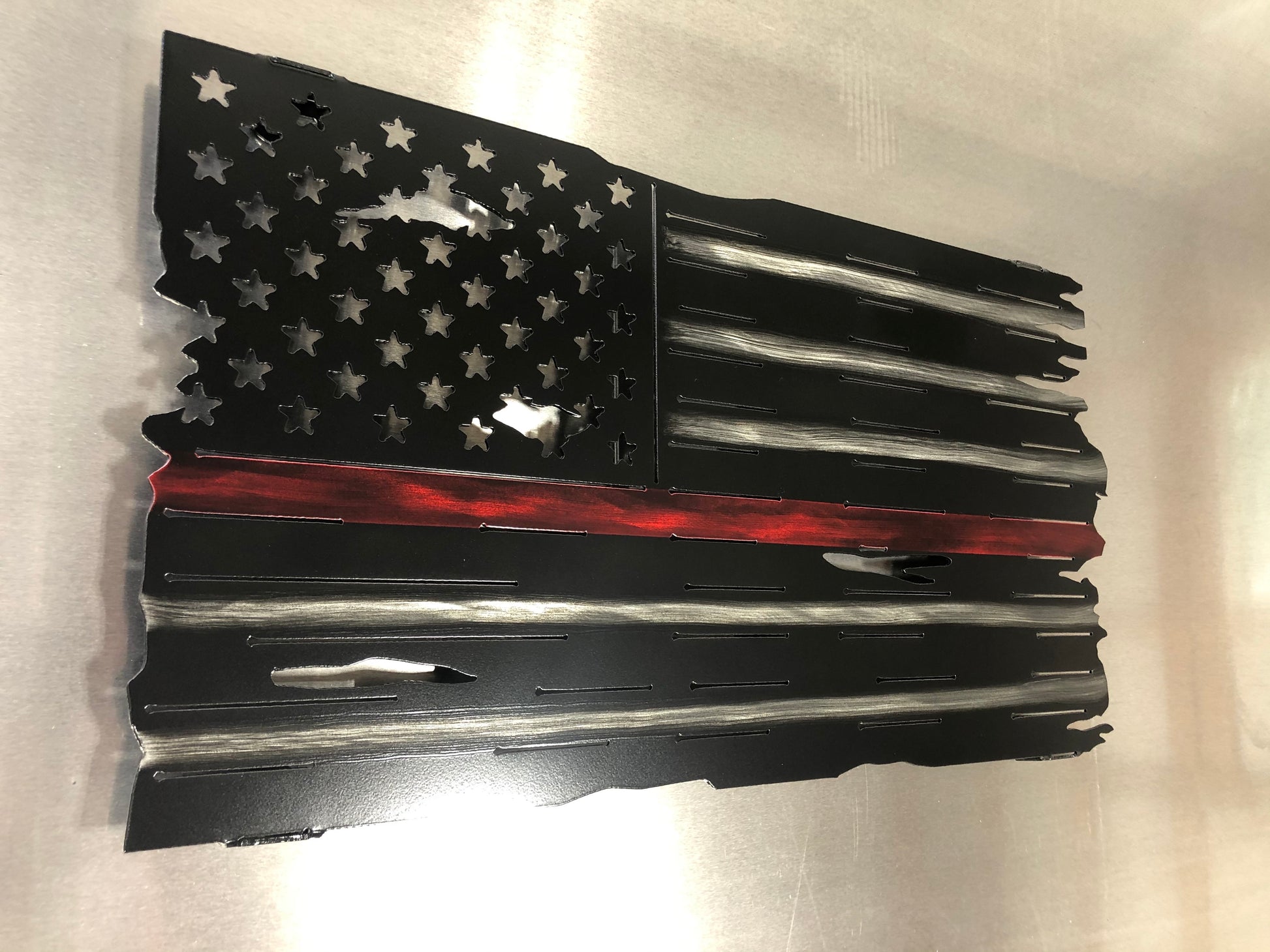 Thin Red Line Distressed American Flag made from metal, featuring a rugged design honoring firefighters. Perfect for home or station display.