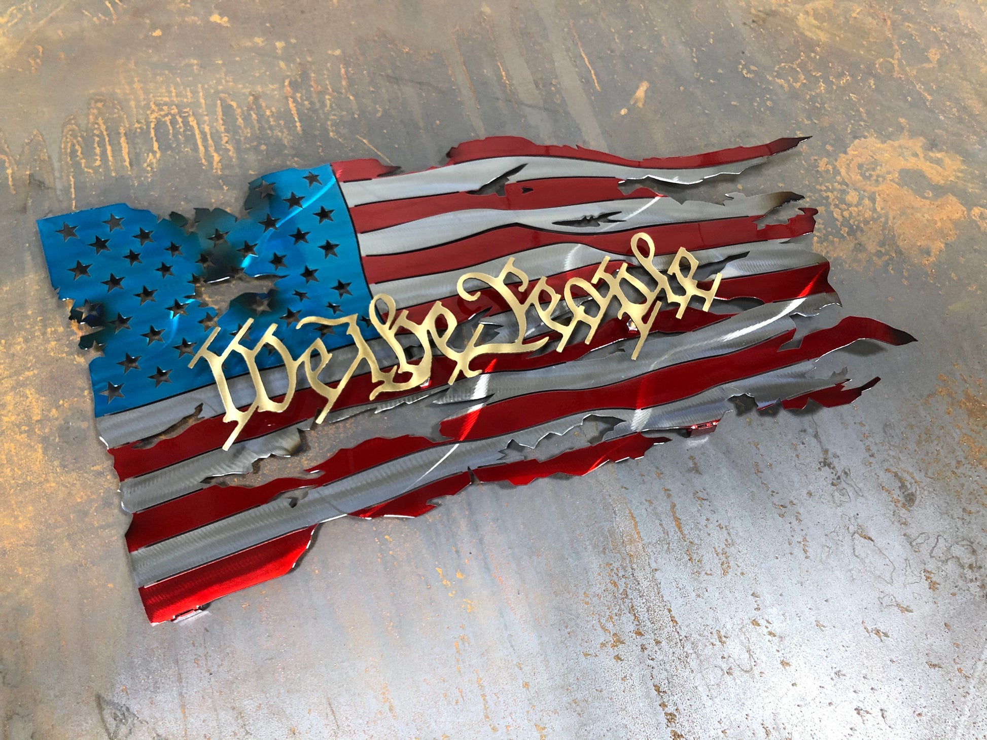 We The People Battle Worn Metal Flag, handcrafted from American steel with a rugged, battle-worn design and powder-coated finish