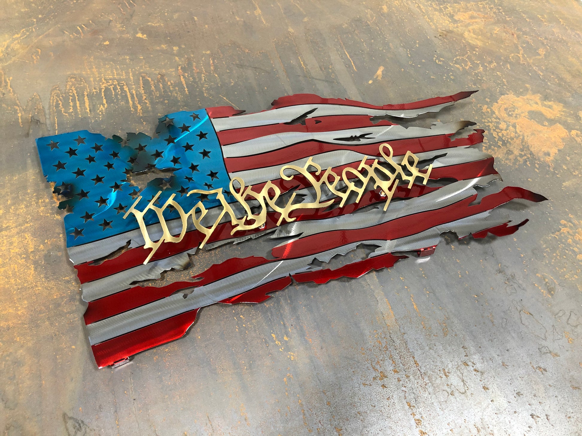 We The People Battle Worn Metal Flag, handcrafted from American steel with a rugged, battle-worn design and powder-coated finish