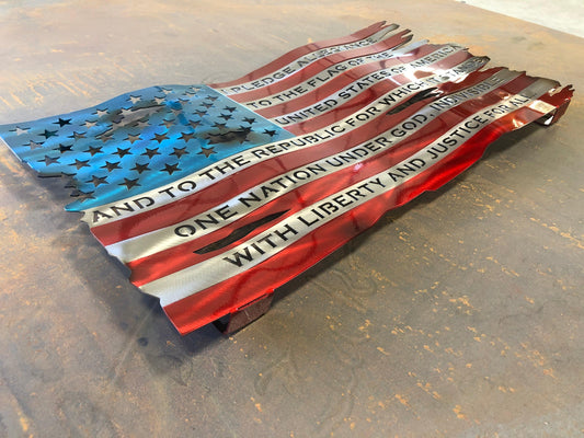 Pledge of Allegiance metal flag with hand-formed waves, heat patina finish, and floating wall mount design, measuring 24 inches wide.